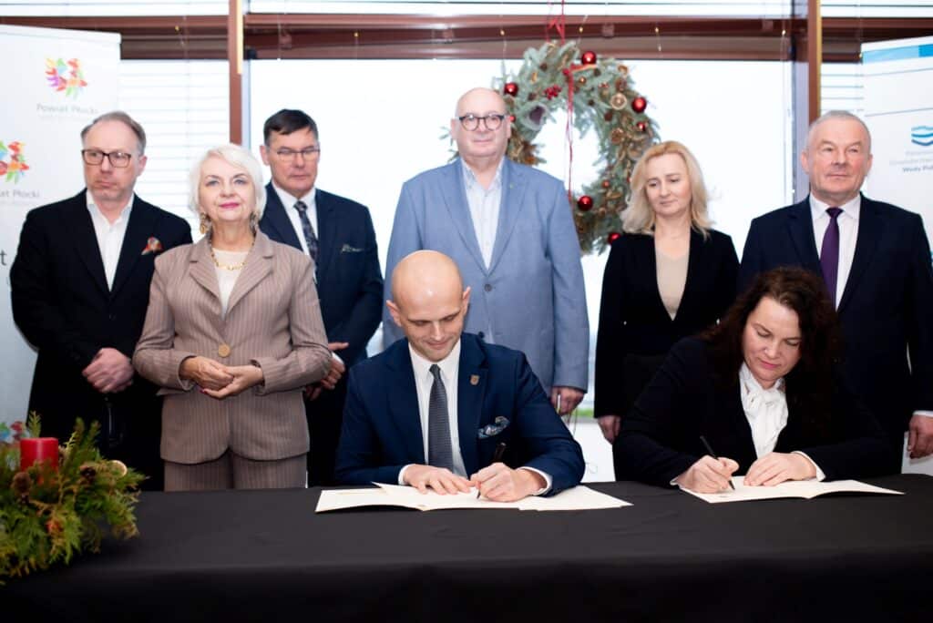 Na zdjęciu prezentuje się grupa osób podczas ceremonii podpisania dokumentów dotyczących przywracania bezpieczeństwa powodziowego w Powiecie Płockim.