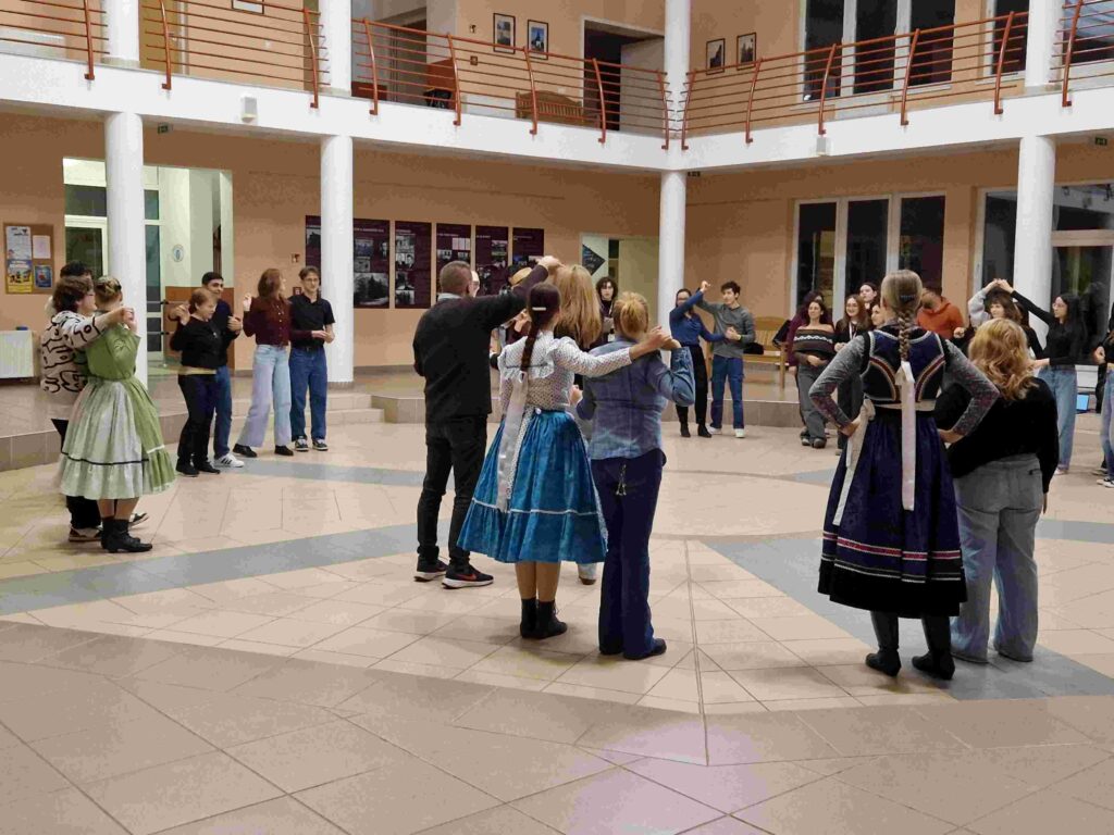 Uczniowie biorący udział w mobilności Erasmus na Węgrzech uczą się lokalnych tańców w grupie.