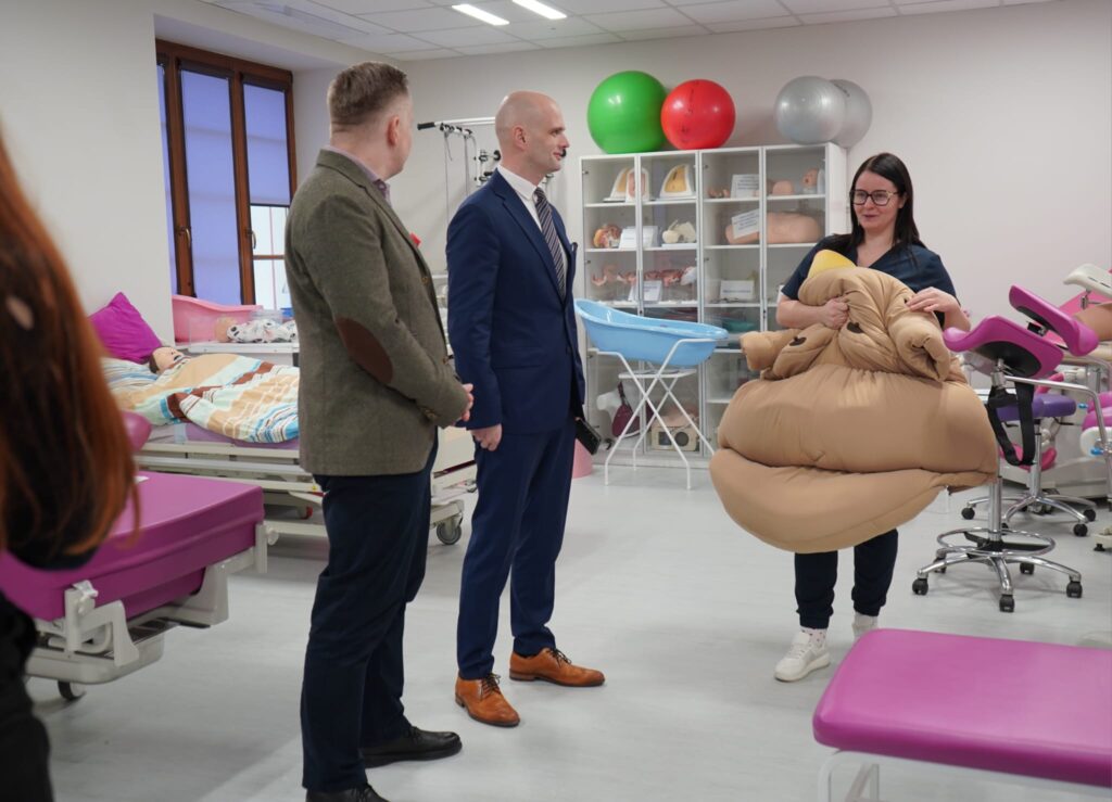 Wiceminister, w towarzystwie samorządowców, obserwuje prezentację sprzętu edukacyjnego podczas wizyty w Powiecie Płockim, podkreślając znaczenie współpracy rządu z samorządem w zakresie bezpieczeństwa.