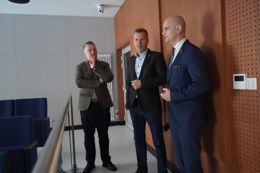 Wiceminister wraz z przedstawicielami samorządu dyskutują na temat bezpieczeństwa i współpracy rządu w nowoczesnym wnętrzu sali konferencyjnej.