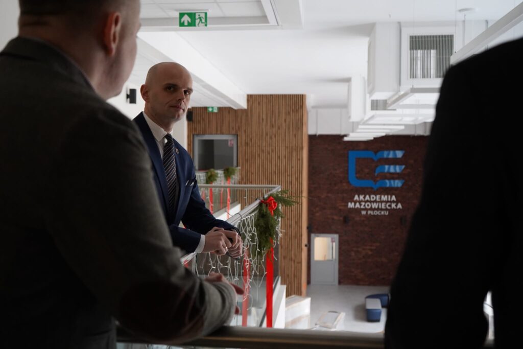 Wiceminister uczestniczy w rozmowie na temat bezpieczeństwa i współpracy między rządem a samorządem podczas wizyty w Akademii Mazowieckiej w Płocku.