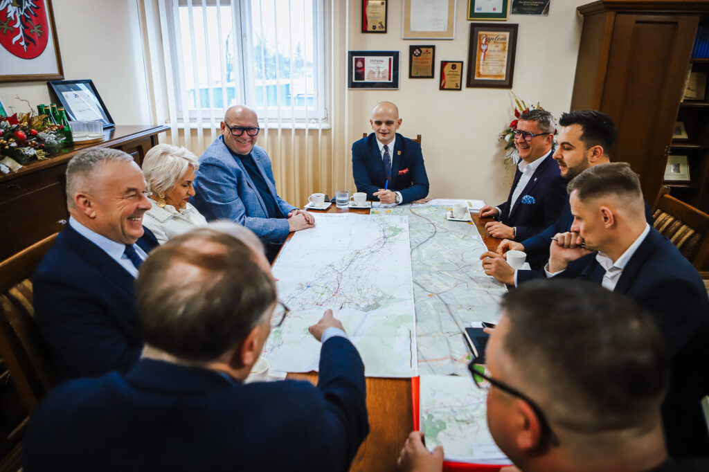 Spotkanie grupy osób przy stole, podczas którego omawiana jest mapa trasy S10 w pobliżu Płocka.