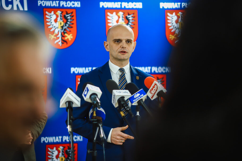 Wiceminister wygłasza przemówienie podczas konferencji prasowej dotyczącej bezpieczeństwa i współpracy rządu z samorządem w Powiecie Płockim.