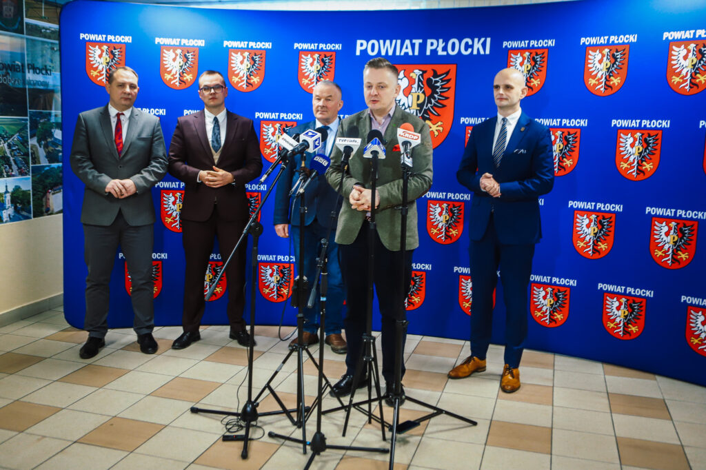 Wiceminister wraz z przedstawicielami samorządu powiatu płockiego uczestniczy w konferencji prasowej na temat bezpieczeństwa i współpracy rządu z lokalnymi instytucjami.