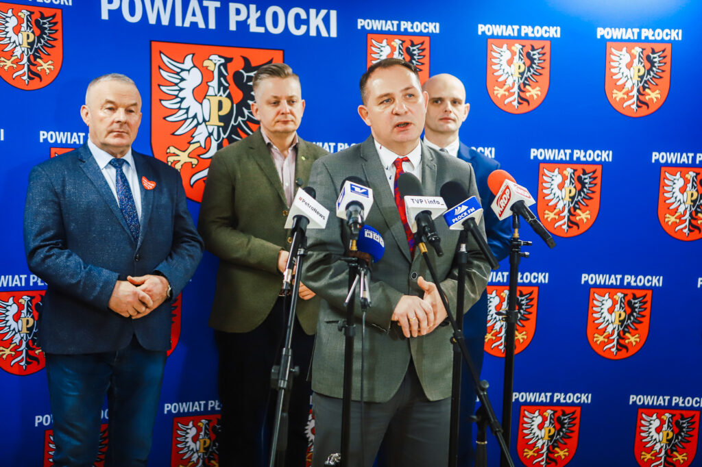 Wiceminister wygłasza przemówienie podczas wizyty w Powiecie Płockim, podkreślając znaczenie współpracy rządu z samorządem w zakresie bezpieczeństwa.