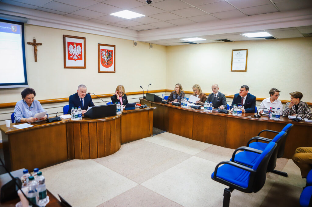 Na zdjęciu przedstawiono XVIII Sesję Rady Powiatu w Płocku, podczas której członkowie rady omawiają ważne kwestie społeczne.