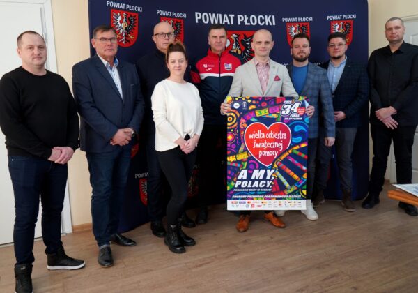 Na zdjęciu widoczna jest grupa ludzi stojących obok siebie, trzymających plakat promujący 34. finał Wielkiej Orkiestry Świątecznej Pomocy.