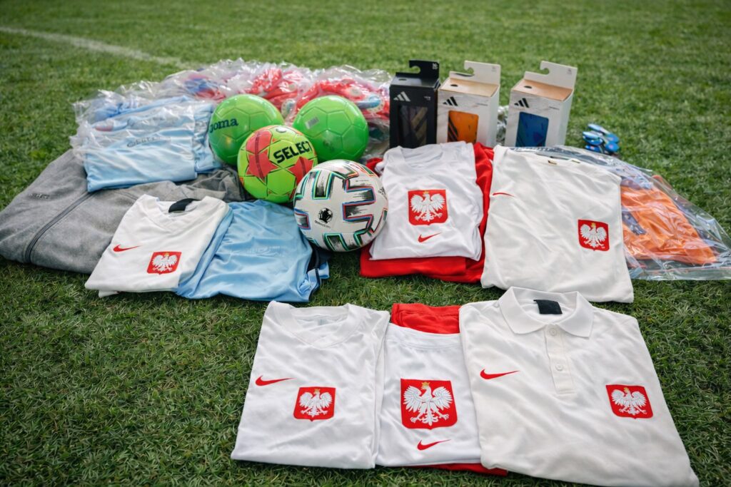 Na zdjęciu widoczne są piłki, odzież sportowa i akcesoria związane z piłką nożną, które zostały zebrane w ramach wsparcia dla Wielkiej Orkiestry Świątecznej Pomocy.