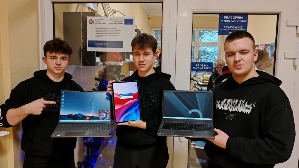 Trzej uczniowie z Zespołu Szkół im. Jana Śniadeckiego w Wyszogrodzie prezentują nowoczesny sprzęt komputerowy, który trafił do ich szkoły w ramach wsparcia edukacji.