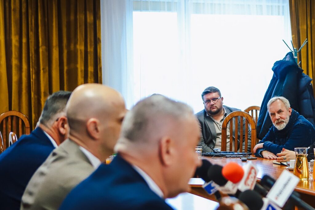 Uczestnicy noworocznego śniadania prasowego samorządowców Powiatu Płockiego z lokalnymi mediami siedzą przy stole z mikrofonami.