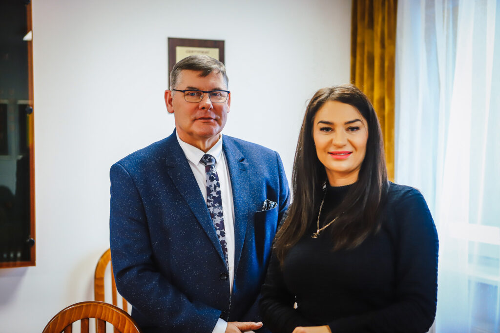 Mężczyzna w granatowym garniturze i kobieta w czarnej bluzce stoją w biurze podczas noworocznego śniadania prasowego samorządowców Powiatu Płockiego z lokalnymi mediami.
