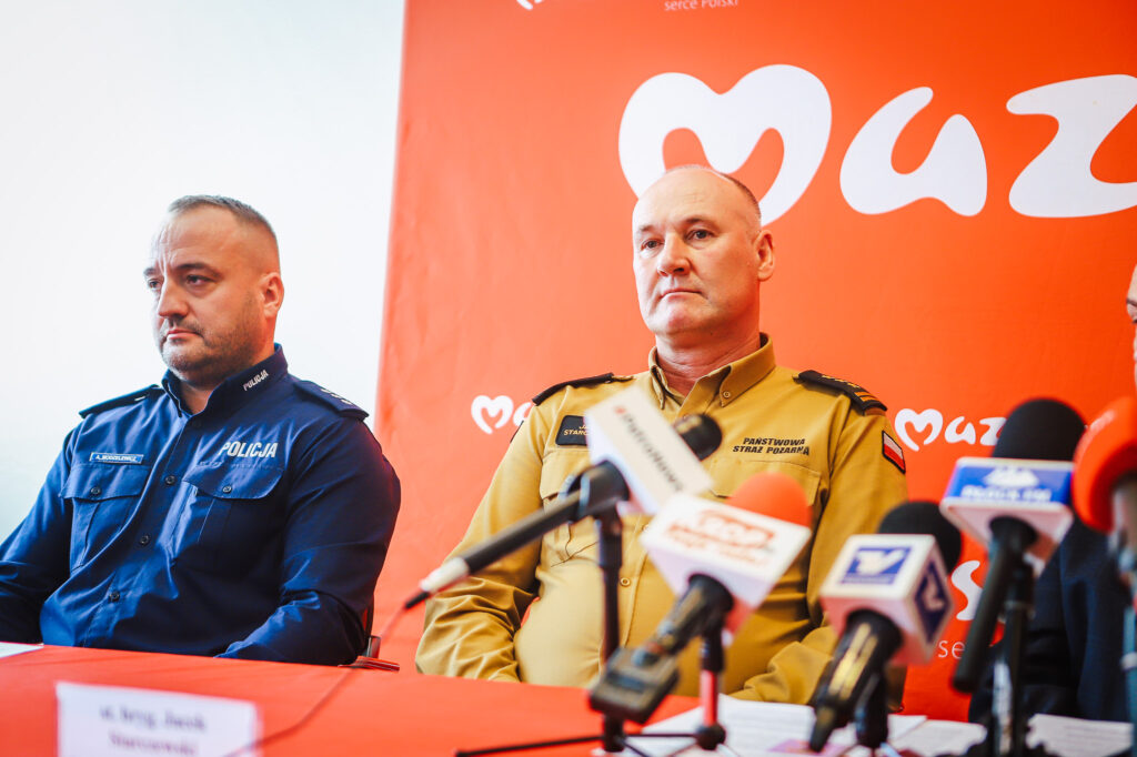Dwóch funkcjonariuszy w mundurach policji i straży pożarnej wygłasza konferencję prasową w Nowym Miszewie dotyczącą zakończenia nielegalnego składowiska odpadów.