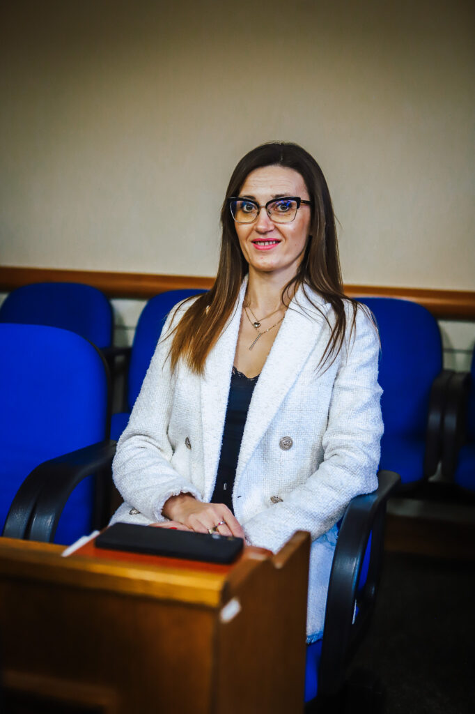 Kobieta z okularami siedzi przy pulpicie w sali obrad podczas XIX sesji Rady Powiatu Płockiego (kadencja 2024–2029).