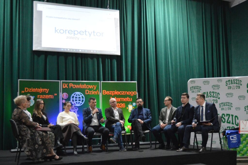 Grupa panelistów siedzących na scenie podczas IX Powiatowego Dnia Bezpiecznego Internetu 2026 w Zespole Szkół im. Stanisława Staszica w Gąbinie, na tle zielonych zasłon i bannerów.