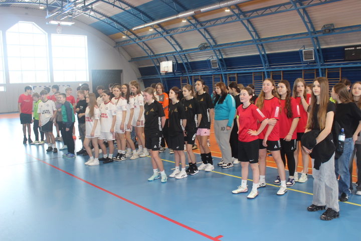Grupa młodych zawodniczek i zawodników stoi w rzędzie na boisku hali podczas powiatowych finałów w halowej piłce nożnej.