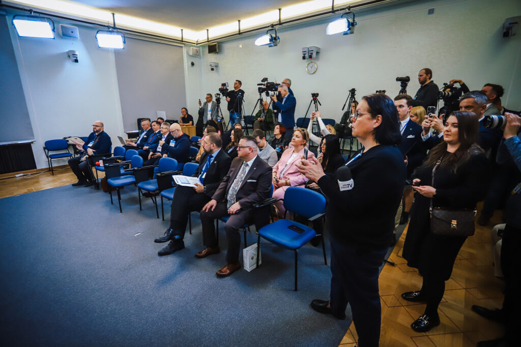 Konferencja prasowa w sali z kamerami i dziennikarzami, podczas której potwierdzono, że trasa S10 będzie przebiegać w pobliżu Płocka.
