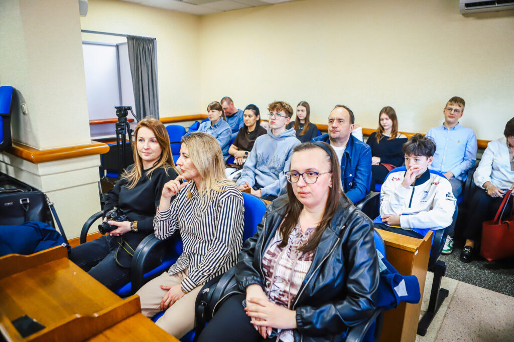 Uczestnicy uroczystości podsumowania finału WOŚP w powiecie płockim siedzą w sali i słuchają prezentacji.