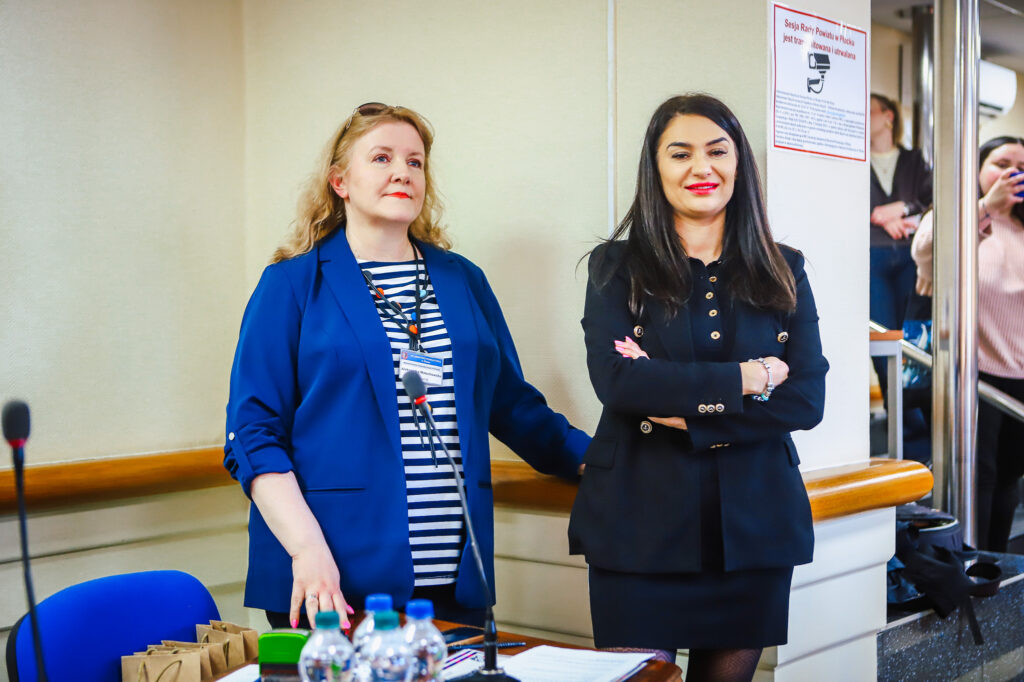 Dwie kobiety stoją przy stole z mikrofonem podczas uroczystego podsumowania tegorocznego Finału WOŚP w powiecie płockim.