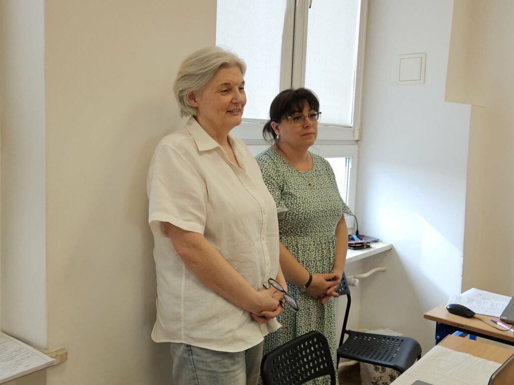 Dwie kobiety stojące obok siebie w biurze przy oknie podczas zakończenia kwalifikacji wojskowej w Powiecie Płockim.